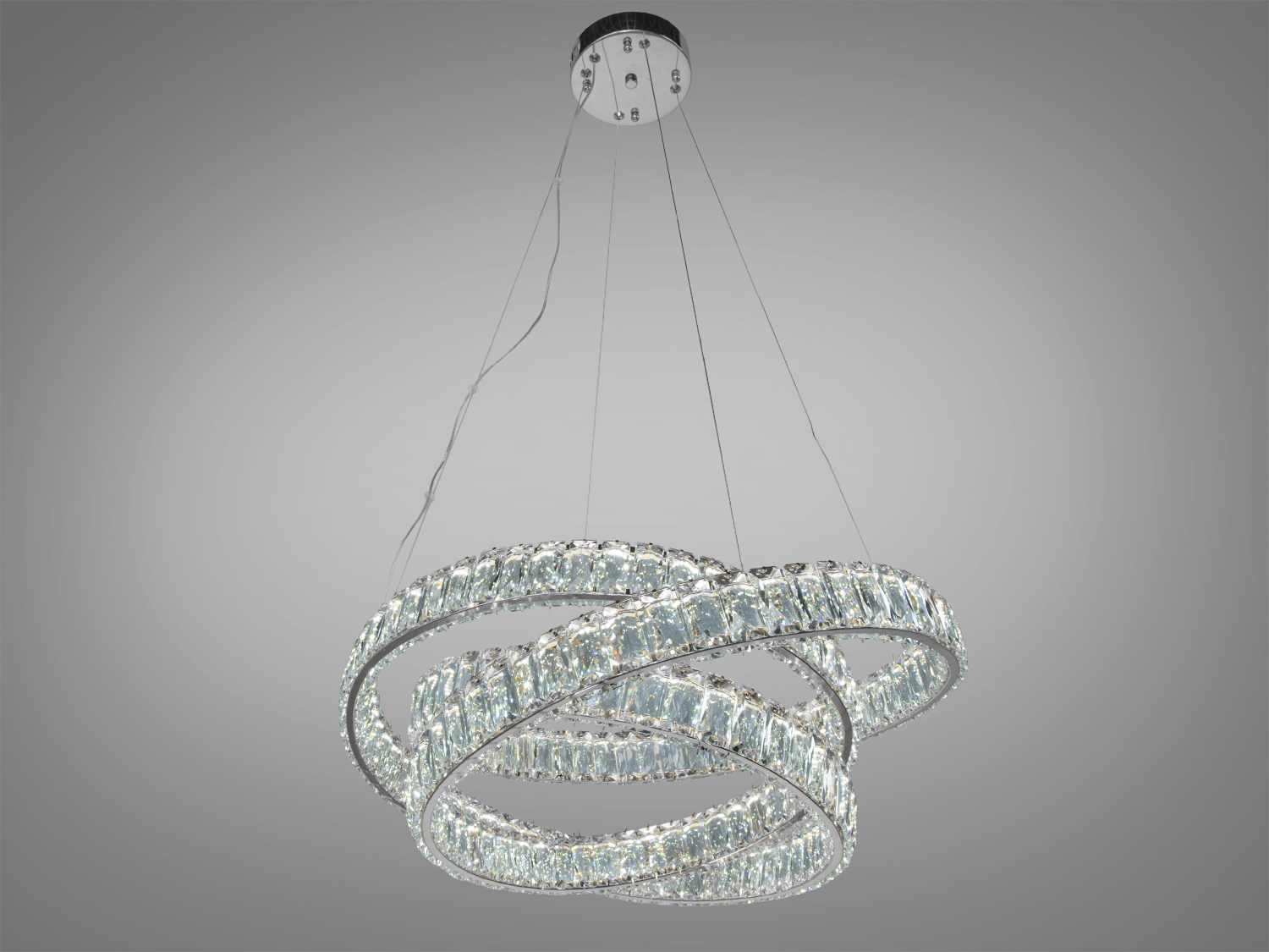 Люстра з трьома кільцями, прикрашена кристалами, підвісна конструкція на стелі. Підходить для вітальні або їдальні.