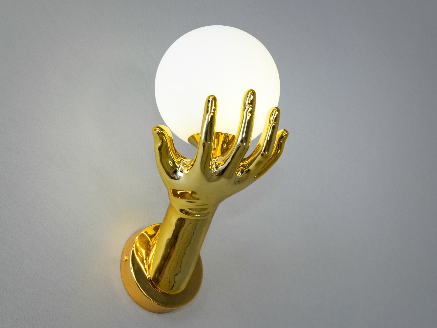 Золотистий настінний світильник у вигляді руки з білою кулею. Підходить для монтажу в сучасних приміщеннях.