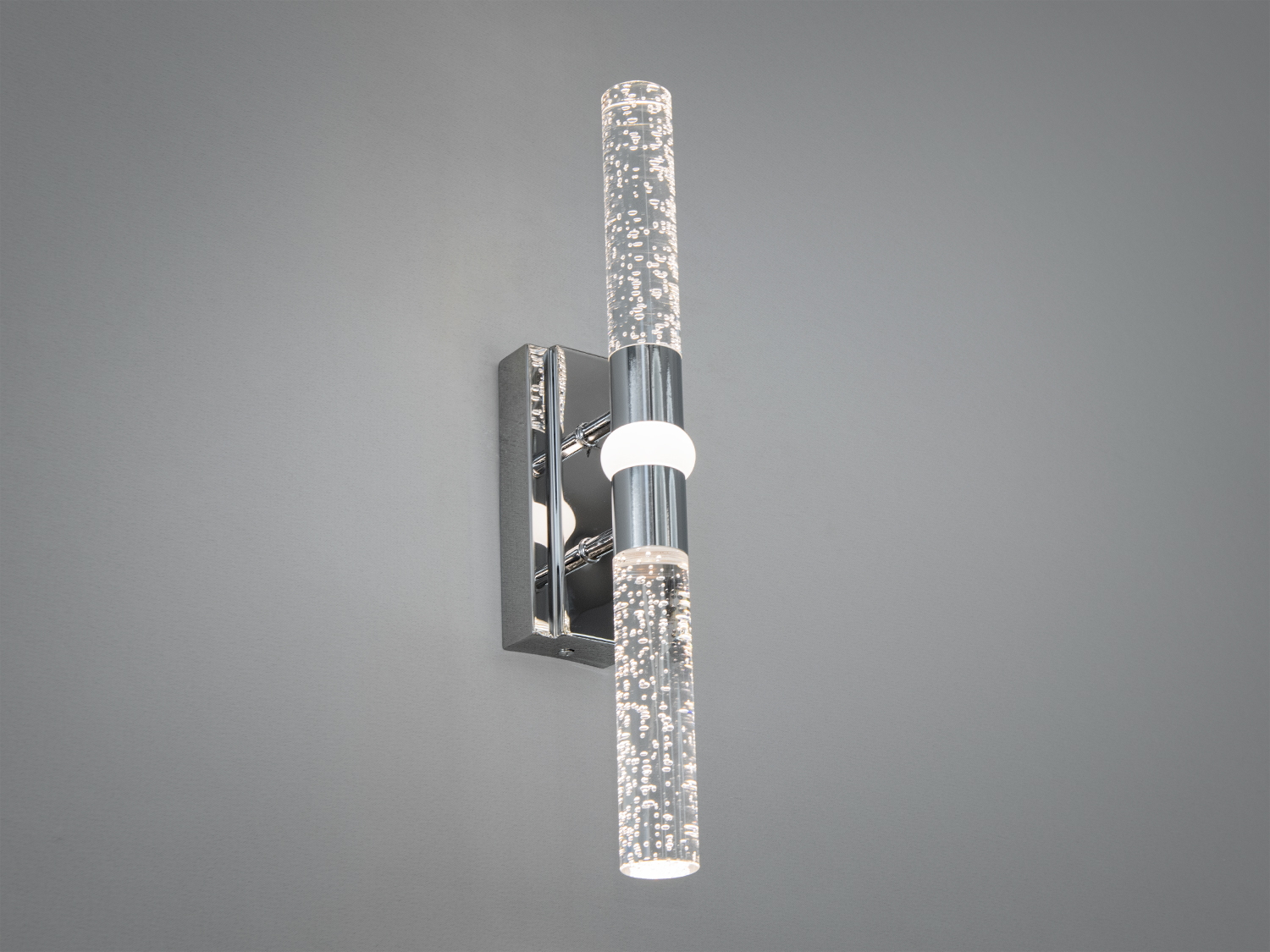 Світильник настінний з двома прозорими циліндрами, що випромінюють м′яке світло. Хромована основа додає елегантності. Підходить для ванної кімнати.