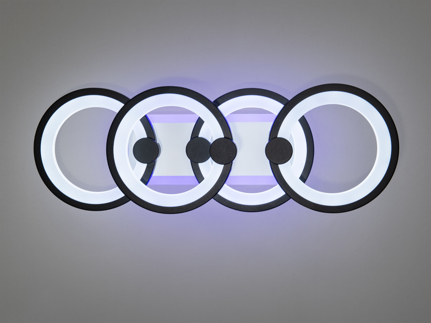 Настінний світильник з чотирма кільцями, що випромінює тепле світло. Пульт дистанційного керування для зручного використання.