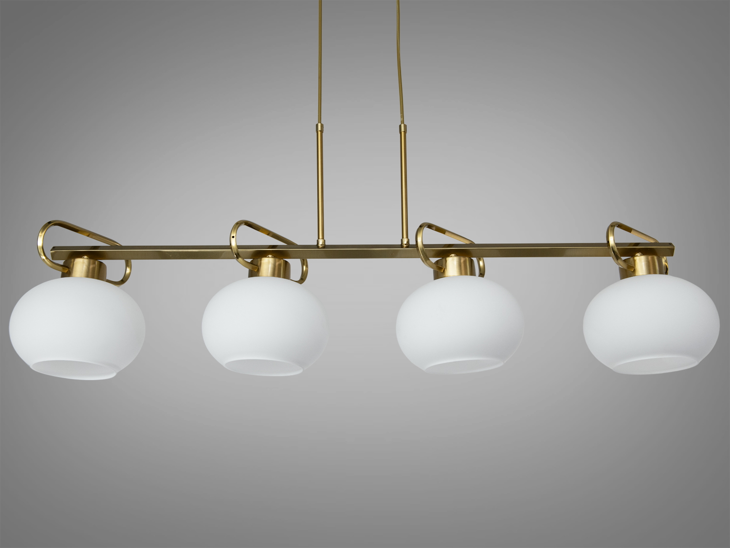 Стильний підвісний світильник з чотирма білими плафонами, закріплений на золотистій планці, підходить для вітальні або кухні.
