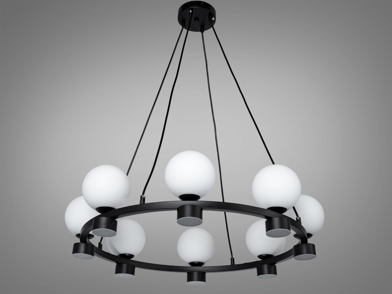 Люстра з білими матовими кулями, підвішена на чорних тросах. Ідеальна для освітлення вітальні.