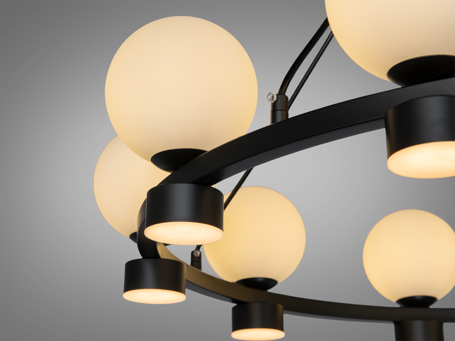 Деталь люстри з теплим жовтим світлом, чорний каркас, підходить для створення затишної атмосфери в кімнаті.