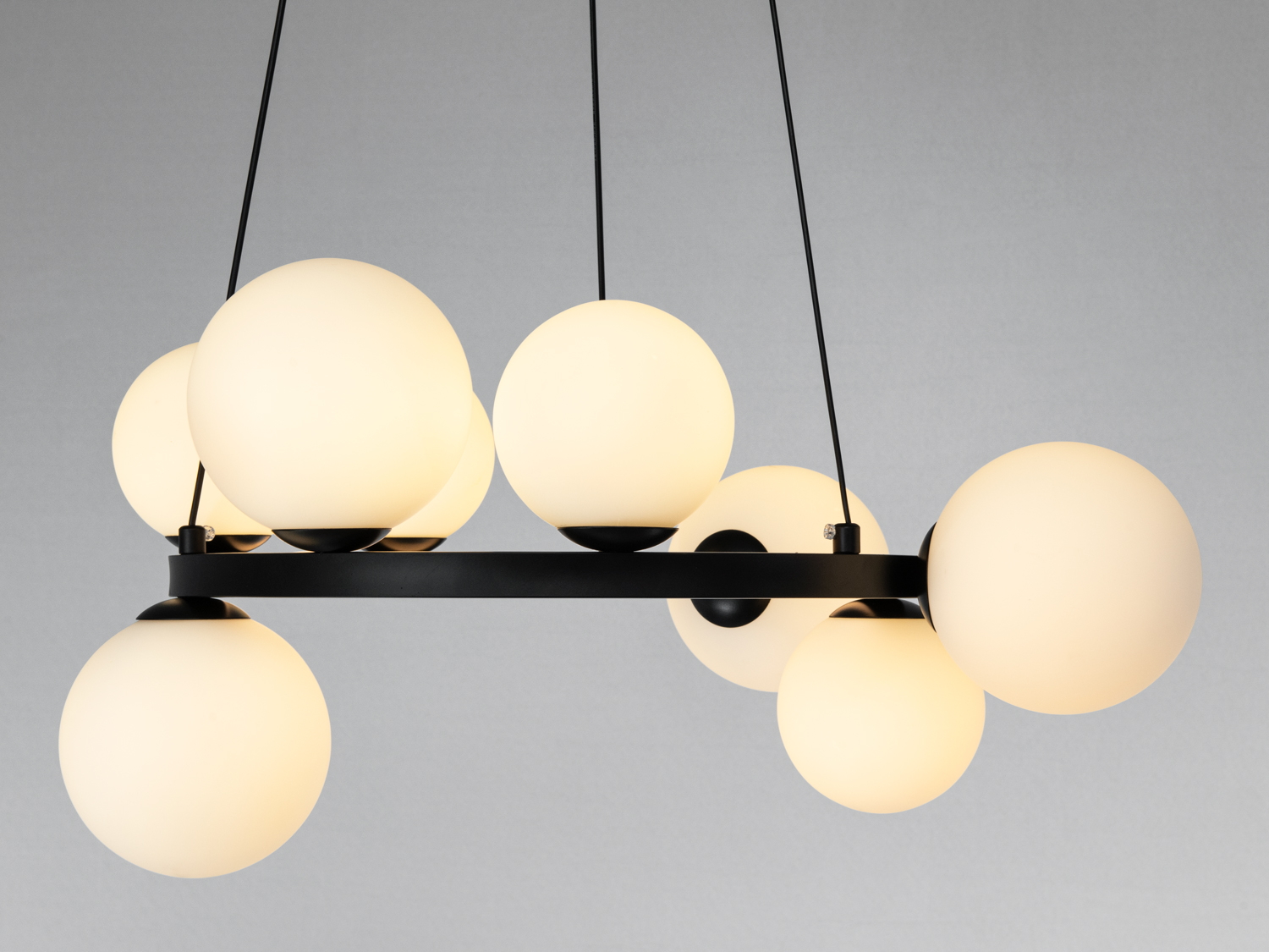 Люстра з шістьма кулястими плафонами, підвішена на тонких тросах, ідеальна для освітлення просторих приміщень з мінімалістичним дизайном.