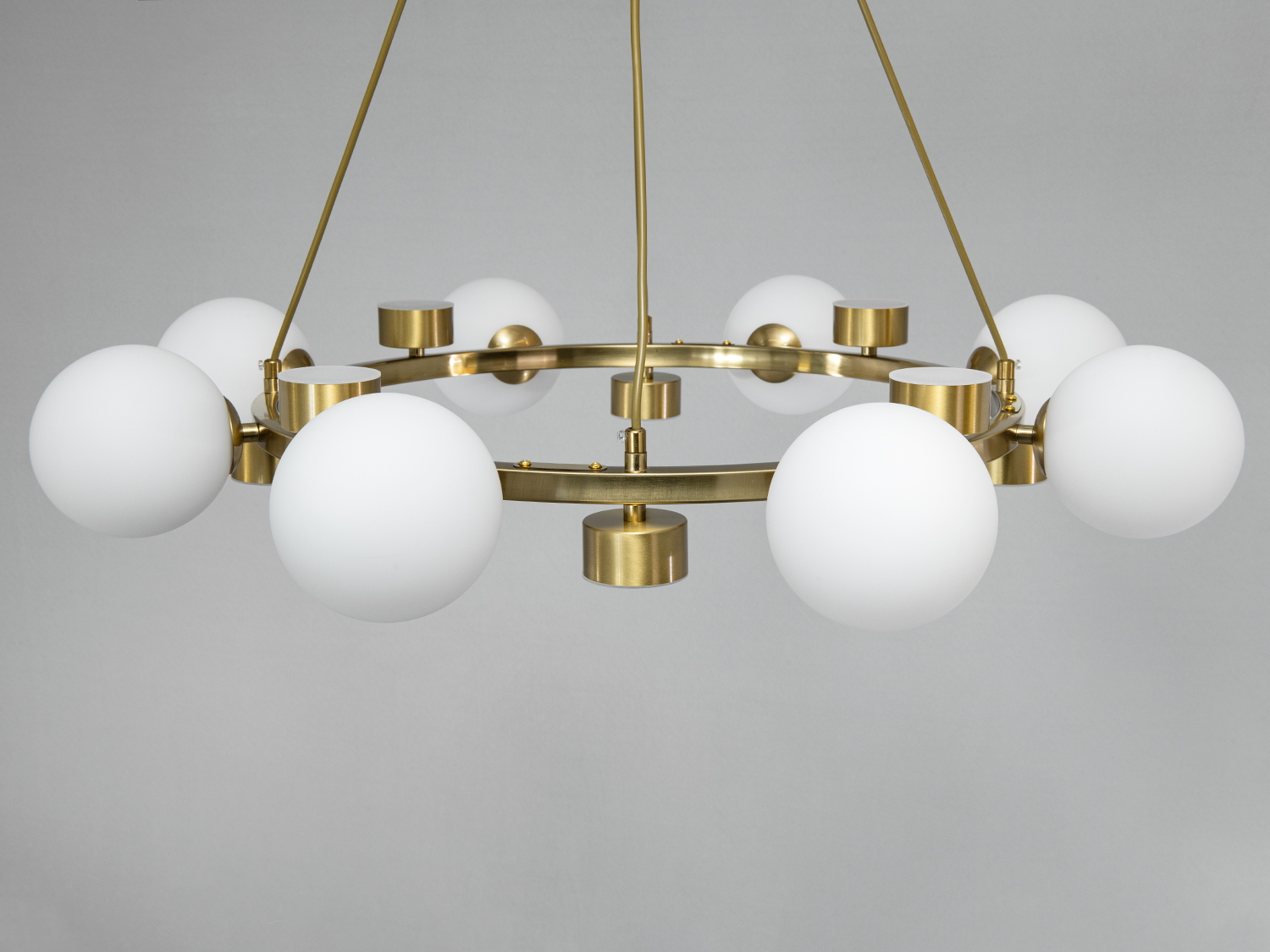 Підвісна люстра з білими кулястими плафонами, встановленими на золотистому кільці. Ідеальна для освітлення просторих кімнат.