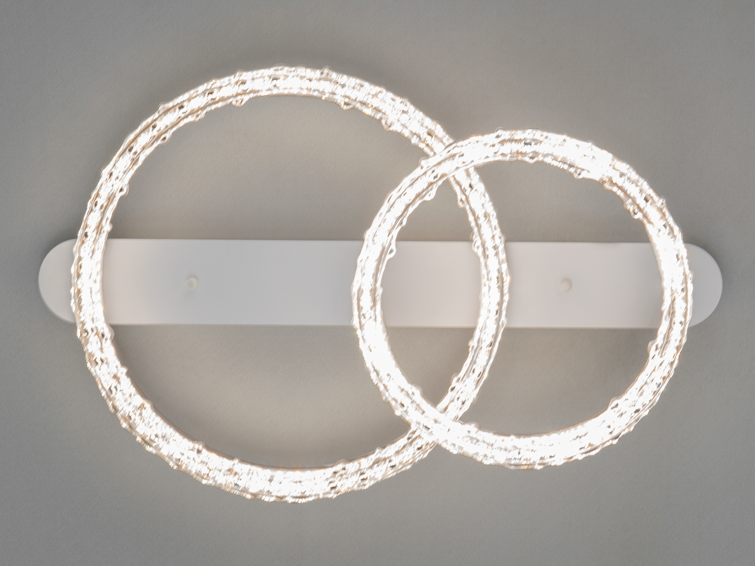 Світильник з двома кільцями, що накладаються, виконаний з прозорого матеріалу. Ідеальний для вітальні.