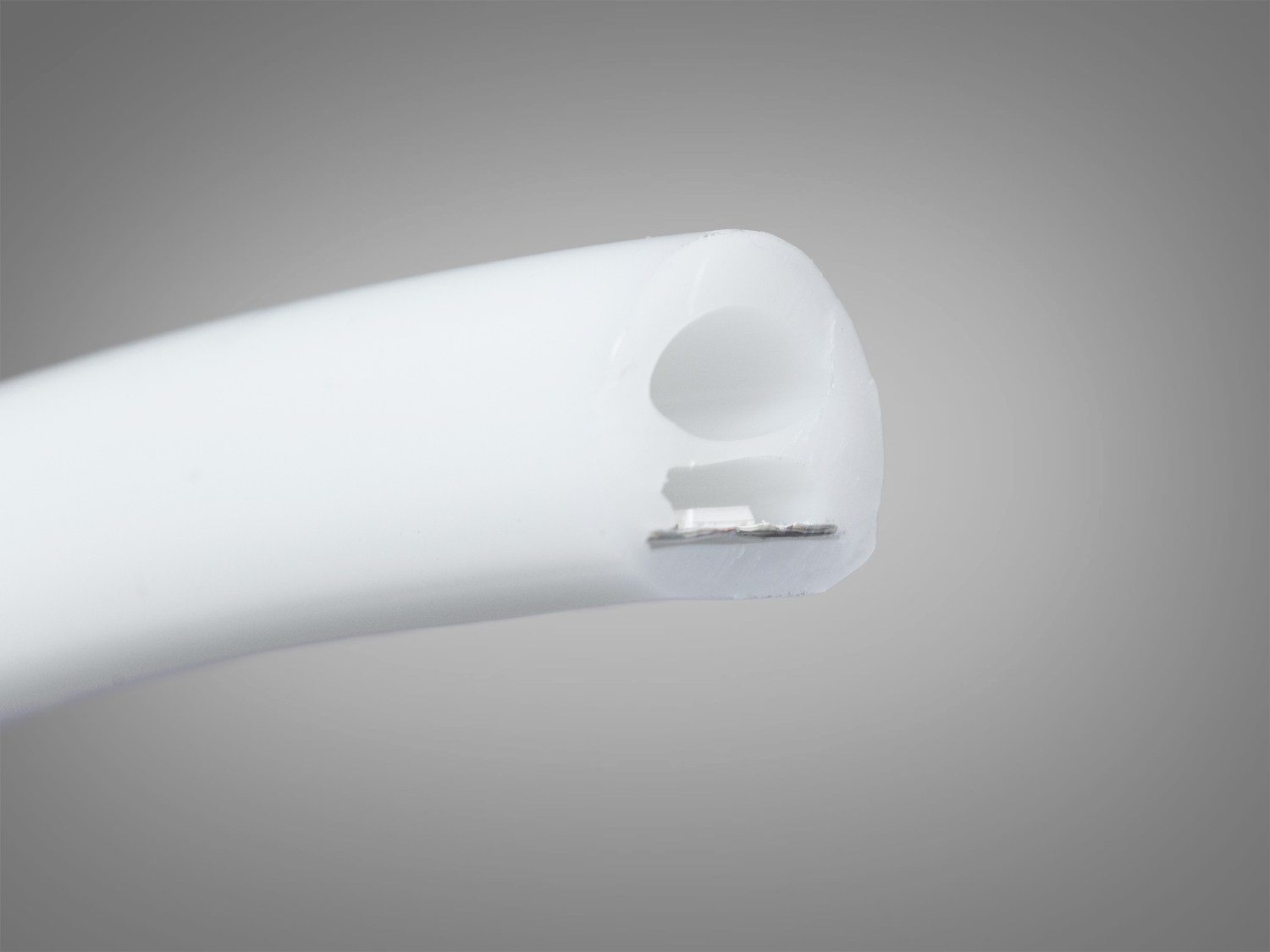 Крупний план кінця світлодіодної стрічки, що показує внутрішню структуру з металевим контактом. Використовується для створення акцентного освітлення.