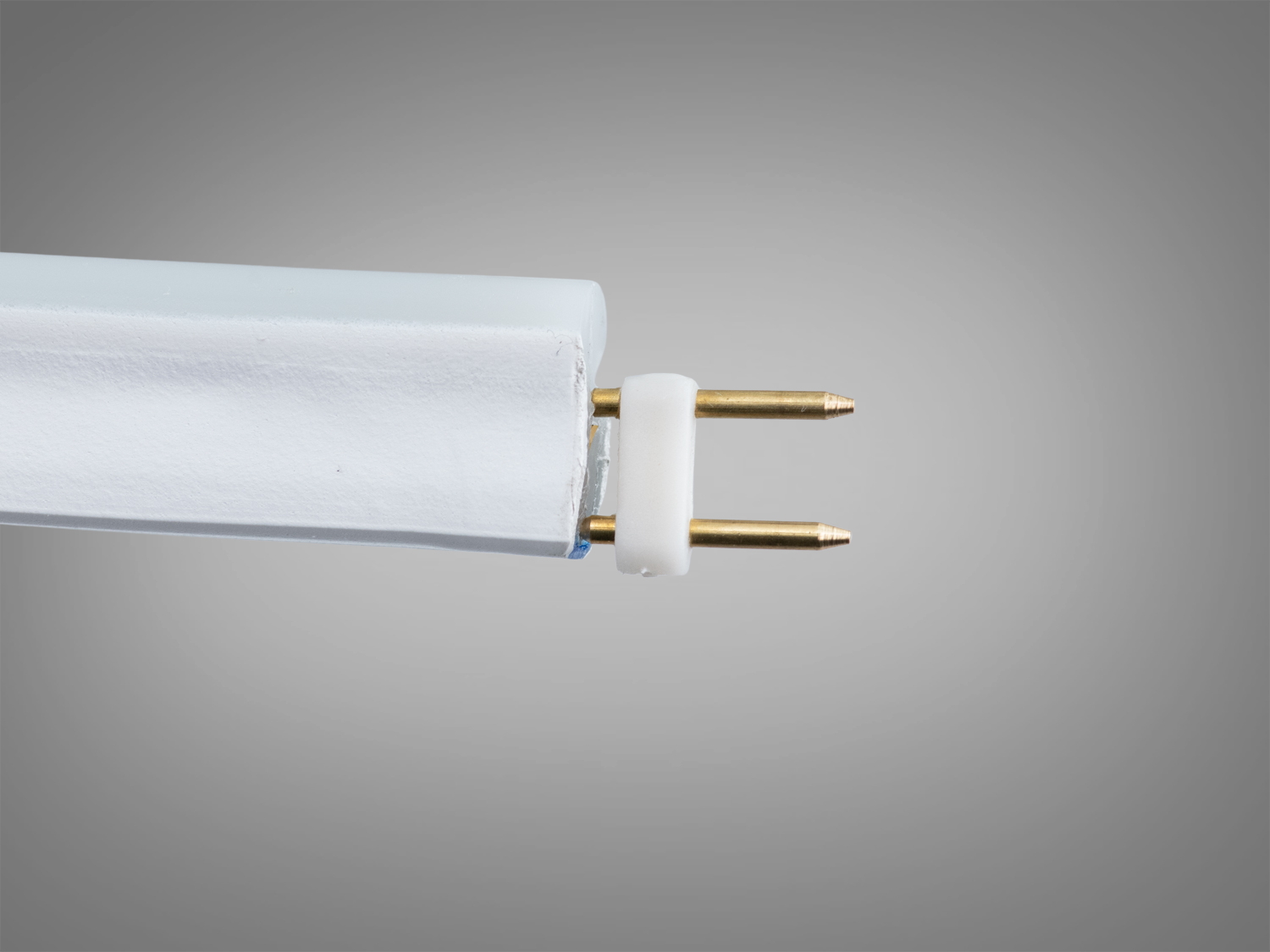 Лінійна лампа з цоколем, що має два металеві контакти, з′єднана з пластиковою основою для використання в світильниках.