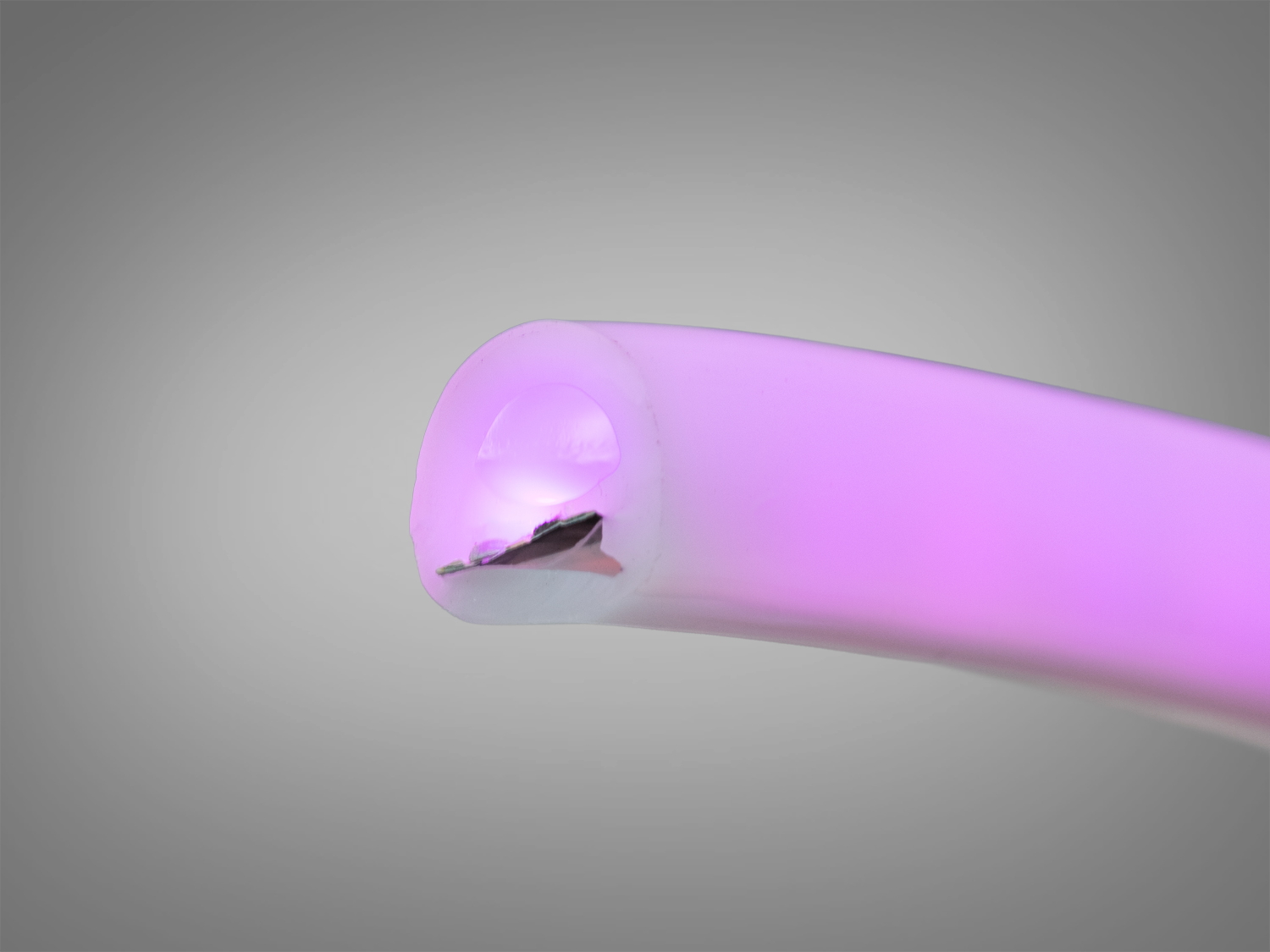 Кінець світлодіодної стрічки з м′яким рожевим світлом, виготовлений із гнучкого матеріалу, що дозволяє легко формувати різні фігури.