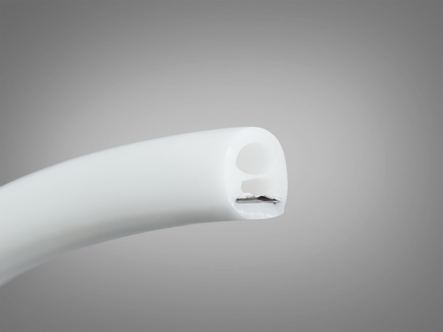 Кінець світлодіодної стрічки з гладкою білою поверхнею, демонструє внутрішню конструкцію. Підходить для монтажу в різних умовах.