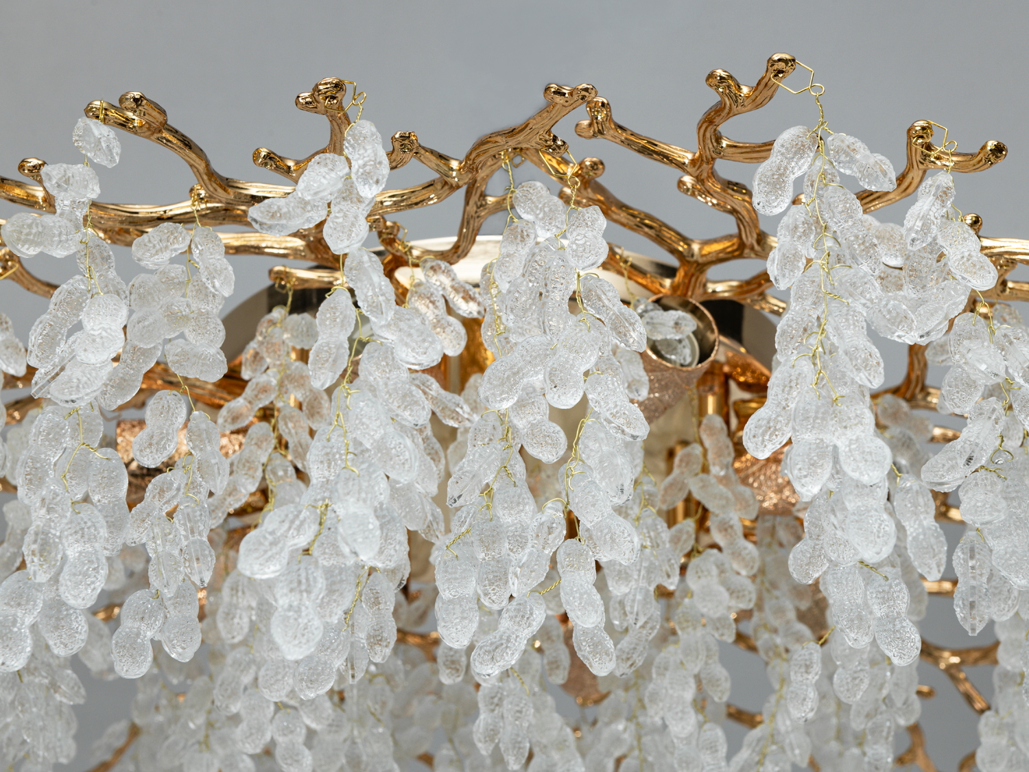 Детальний вигляд світильника з гілками, покритими золотом, та підвісками з текстурованого кришталю, що підкреслюють розкішний стиль.
