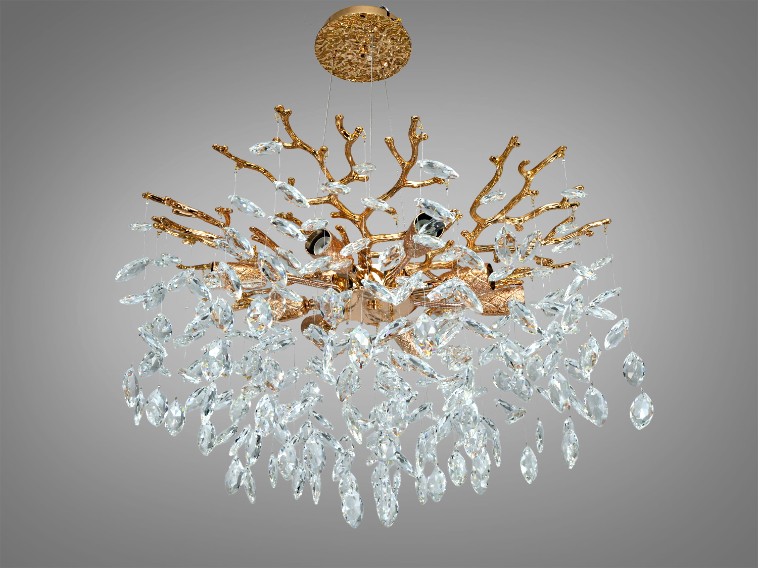 Люстра з кришталевими підвісками на золотистій основі, що має форму розгалужених гілок, створює елегантний світловий ефект.