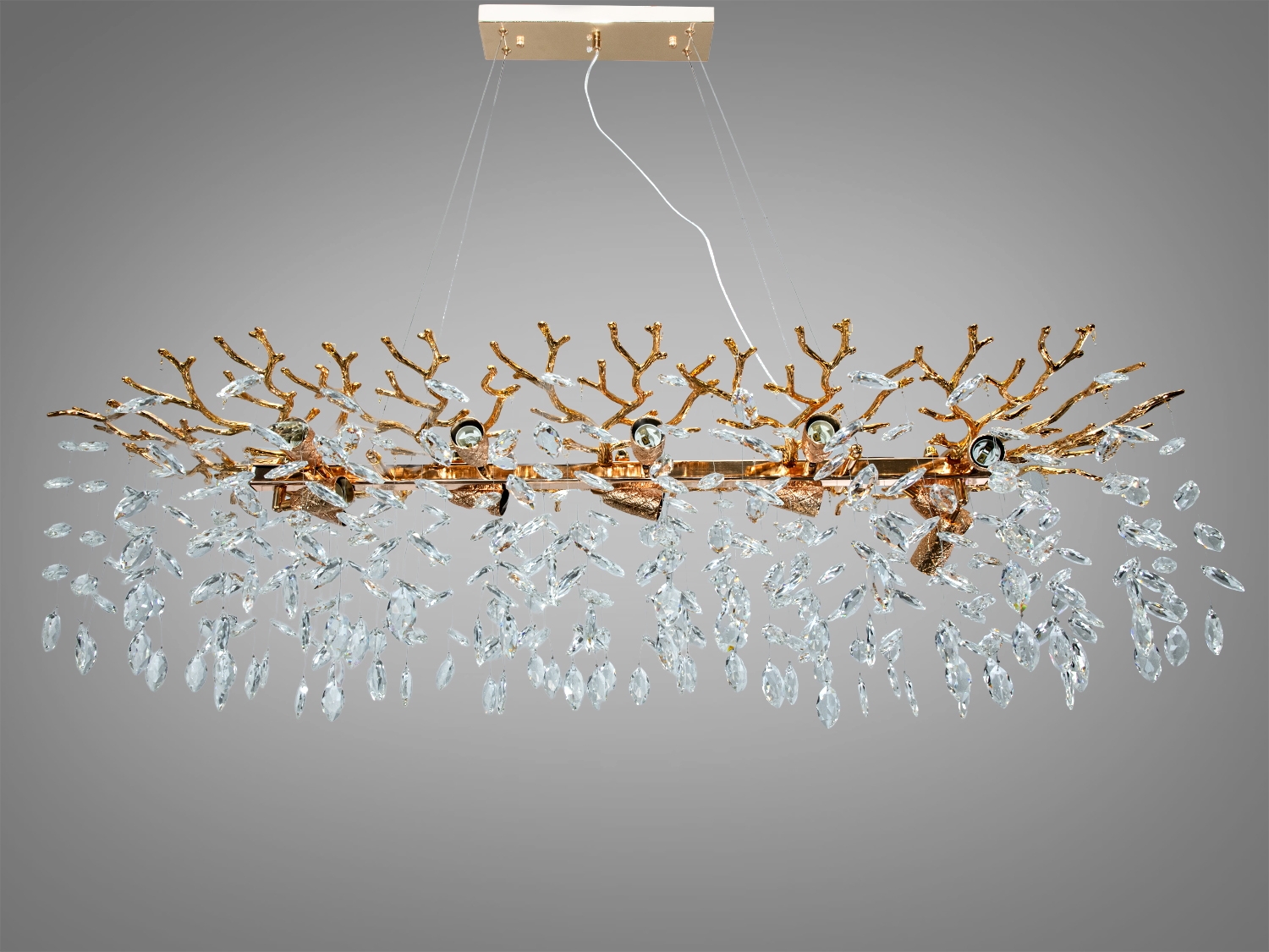 Люстра з кришталевими підвісками, що нагадують краплі води, на золотистій основі. Ідеальна для віталень з високими стелями.