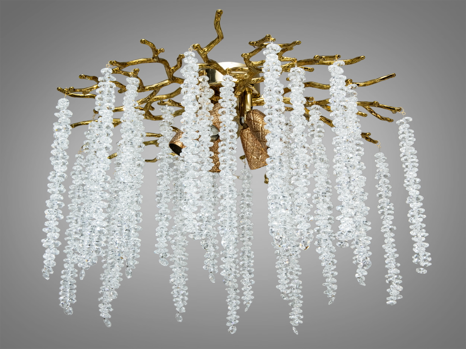 Люстра з кришталевими підвісками, що звисають з гіллястої золотистої основи, створює ефект водоспаду в інтер′єрі.