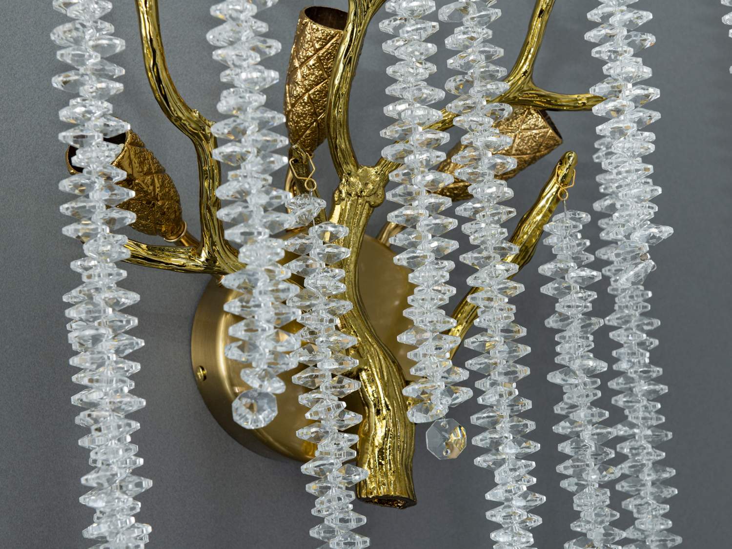 Детальний вигляд настінного світильника з бронзовими гілками та кришталевими підвісками, що підкреслює текстуру матеріалів.