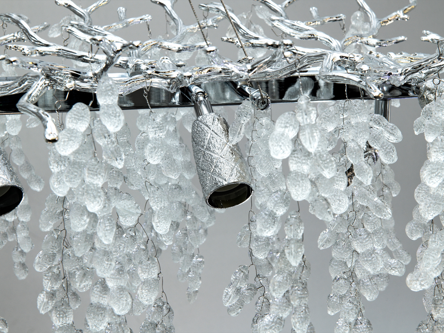 Близький план люстри з текстурованими кришталевими підвісками та металевими елементами, що додають елегантності.