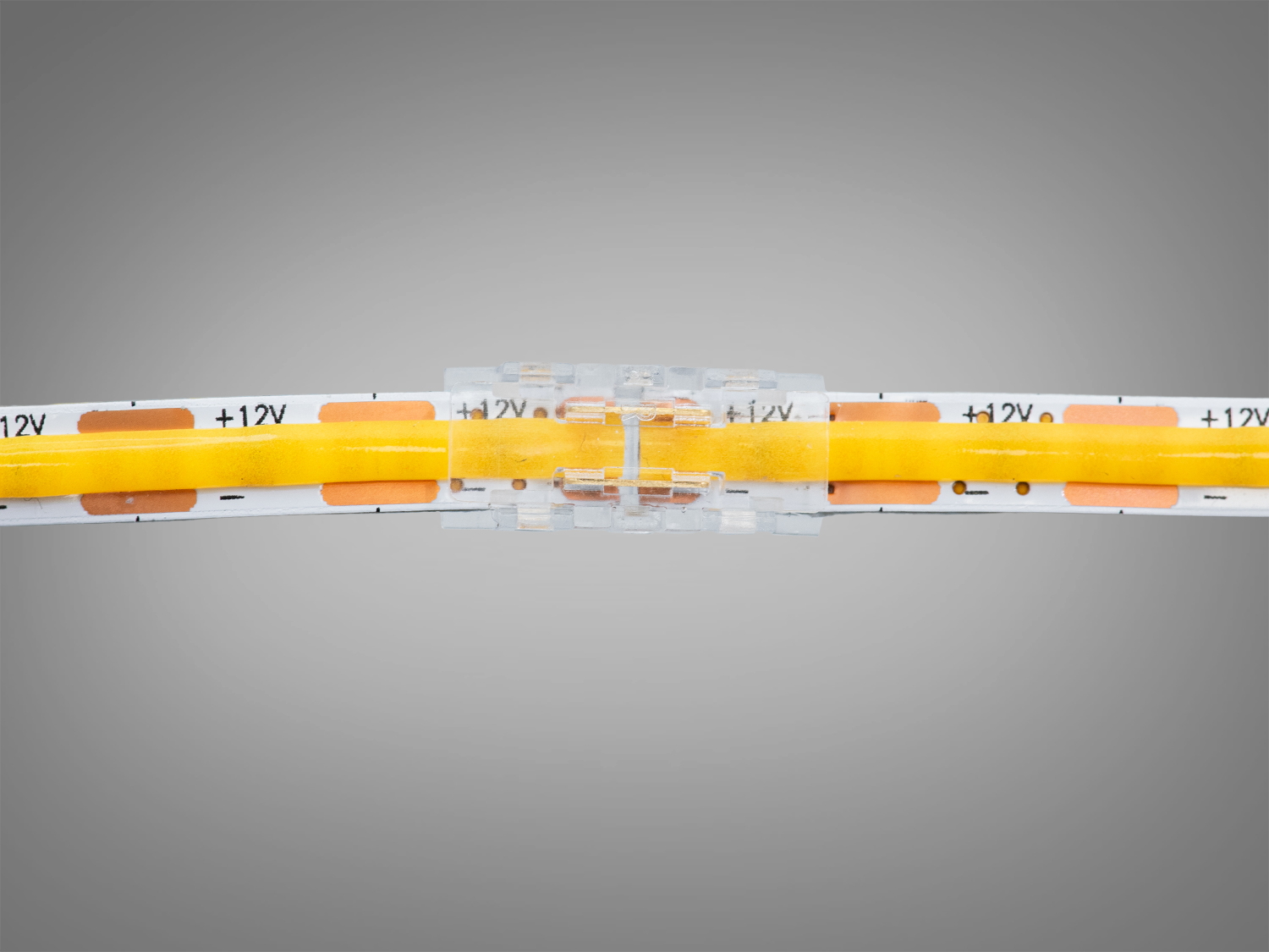 Конектор для LED-стрічки, що з′єднує дві частини. Прозорий корпус дозволяє бачити контакти, забезпечуючи надійне електричне з′єднання.