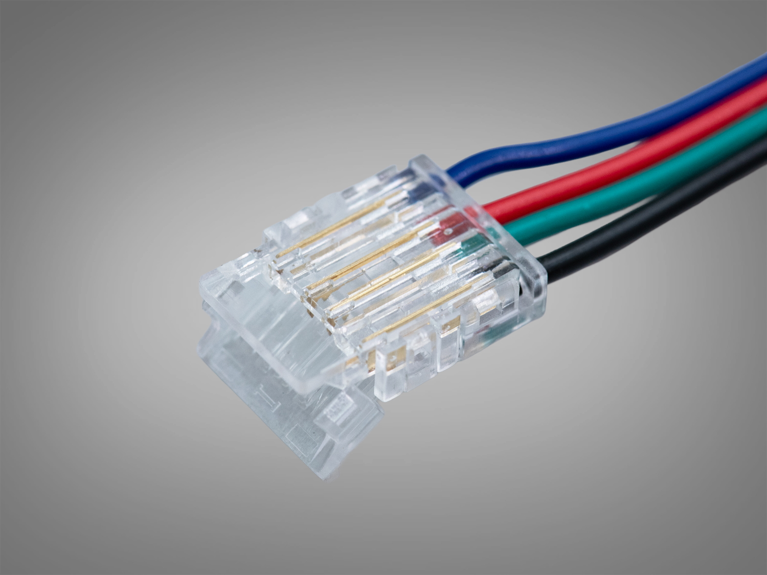 Крупний план прозорого роз′єму з чотирма кольоровими проводами: чорний, зелений, червоний, синій. Використовується для світлодіодних систем.