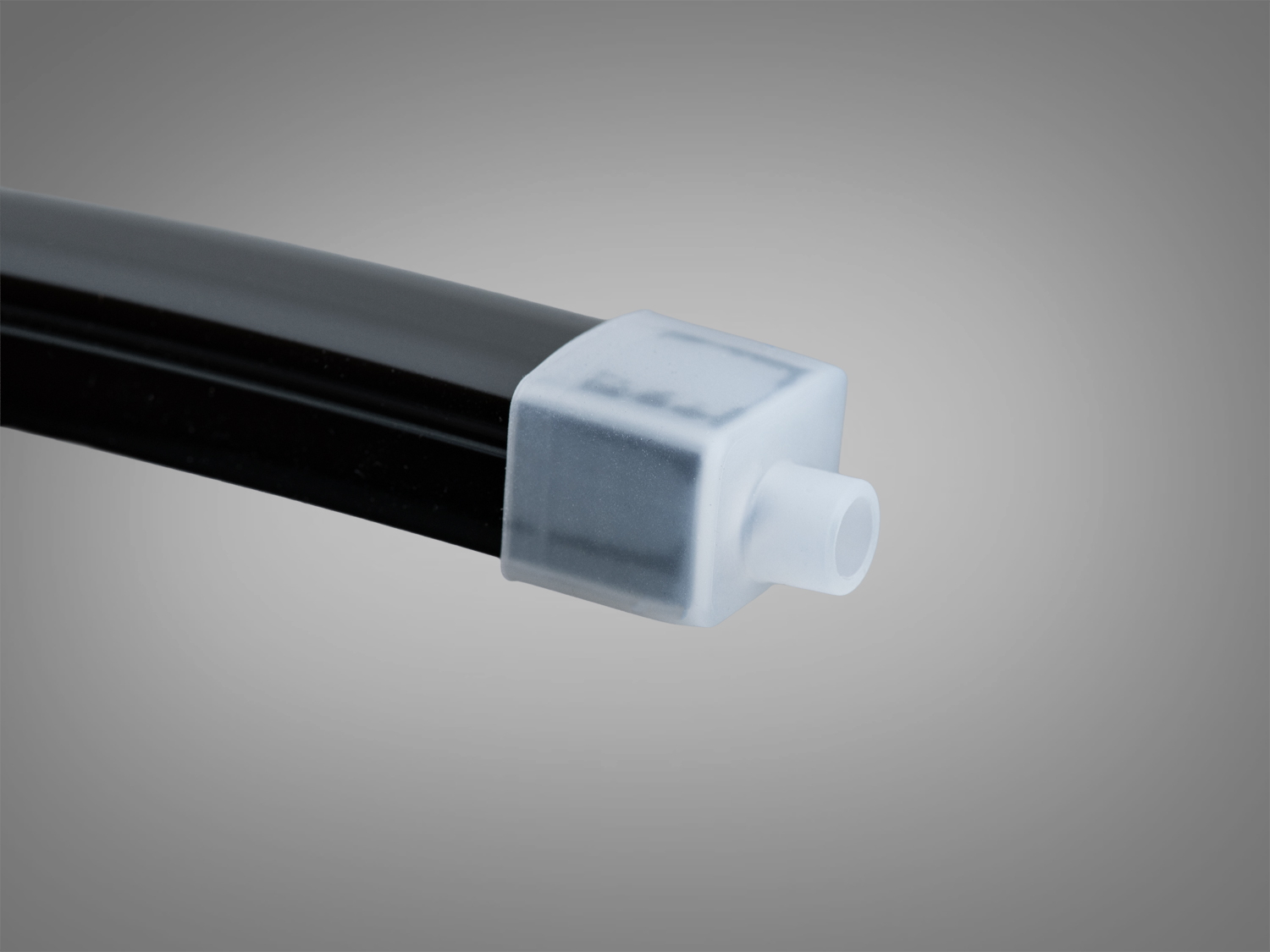 Білий пластиковий ковпачок на чорній трубі, квадратної форми, з отвором. Використовується для захисту кінців труб у промислових умовах.