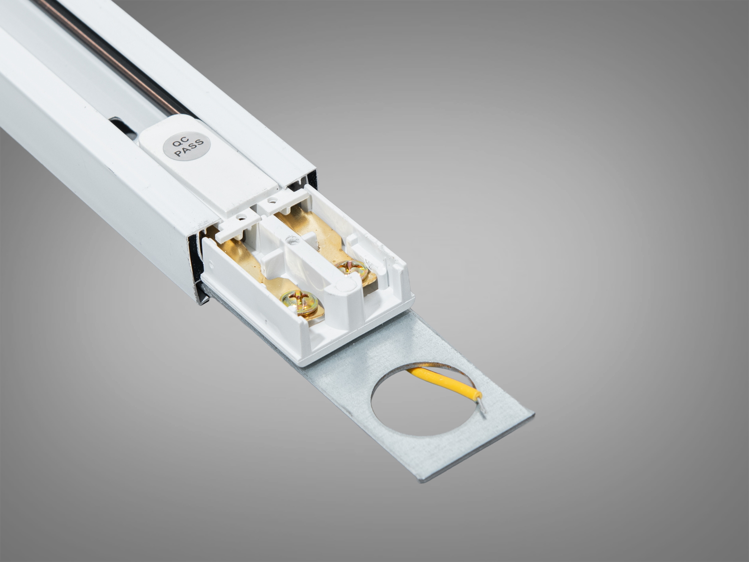 Трековий профіль з монтажним елементом, що включає металеву пластину з отвором і жовтим проводом для електричного з′єднання.