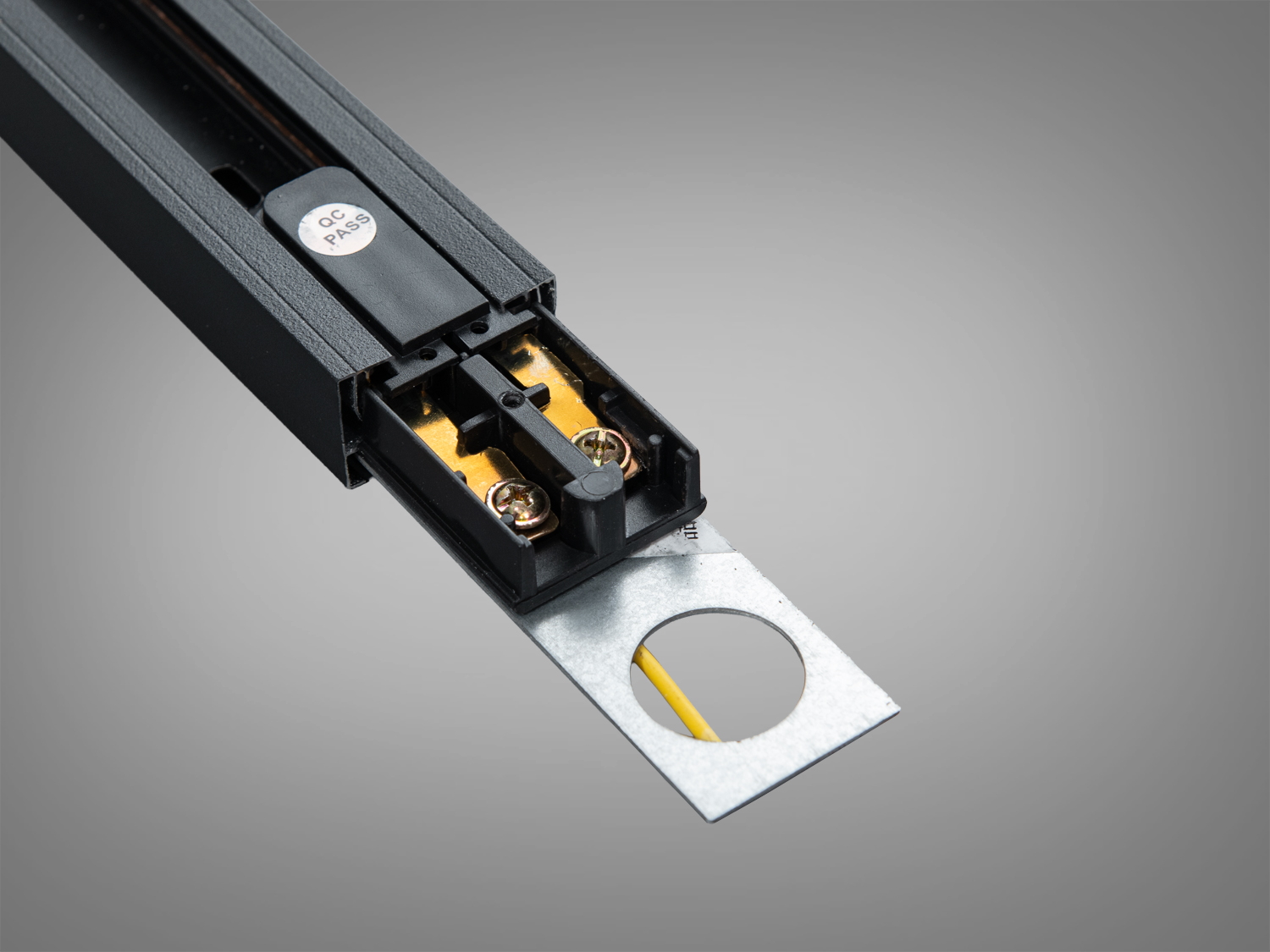 Кінець чорного профілю з видимими контактами та металевою пластиною для кріплення. Використовується в системах трекового освітлення.