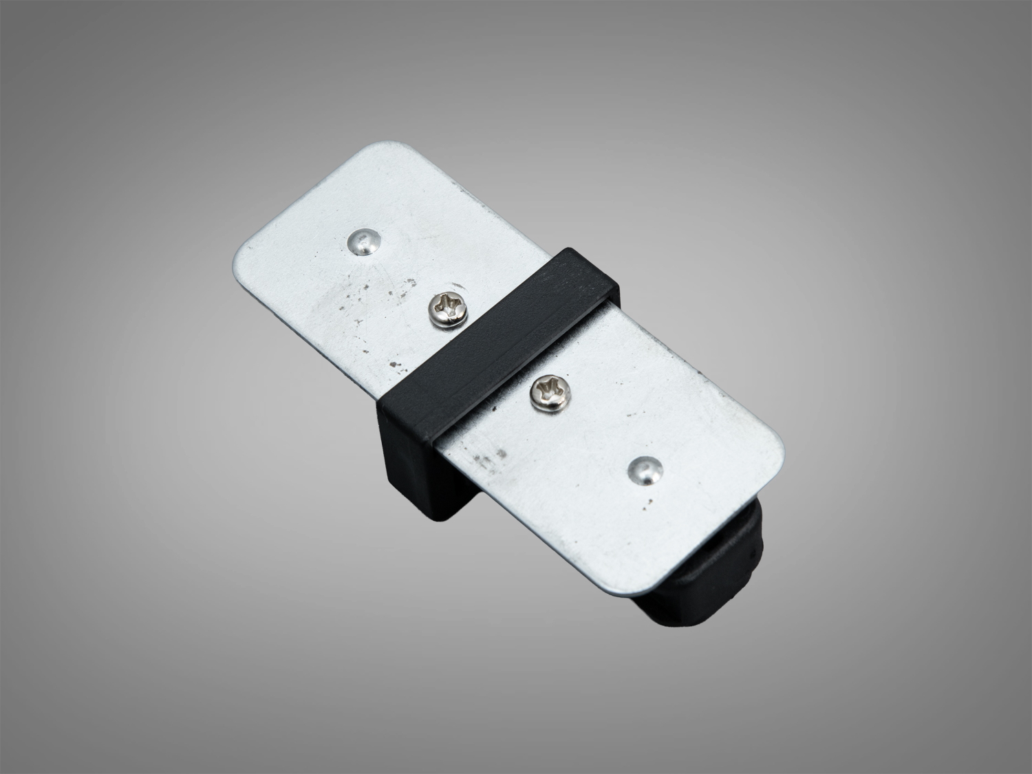 Металева пластина з чорним кріпленням, що має два гвинти для монтажу. Призначена для використання у внутрішніх приміщеннях.