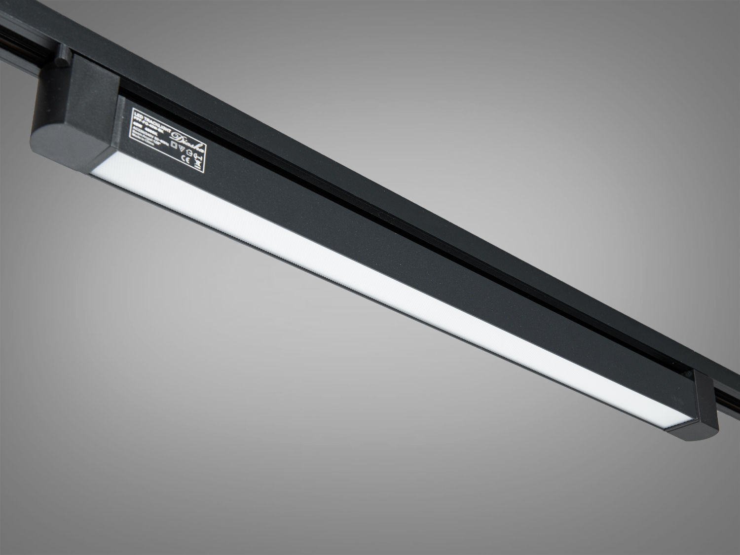 Трековий світильник з чорним корпусом, оснащений світлодіодною панеллю, забезпечує рівномірне освітлення, ідеальний для комерційних приміщень.