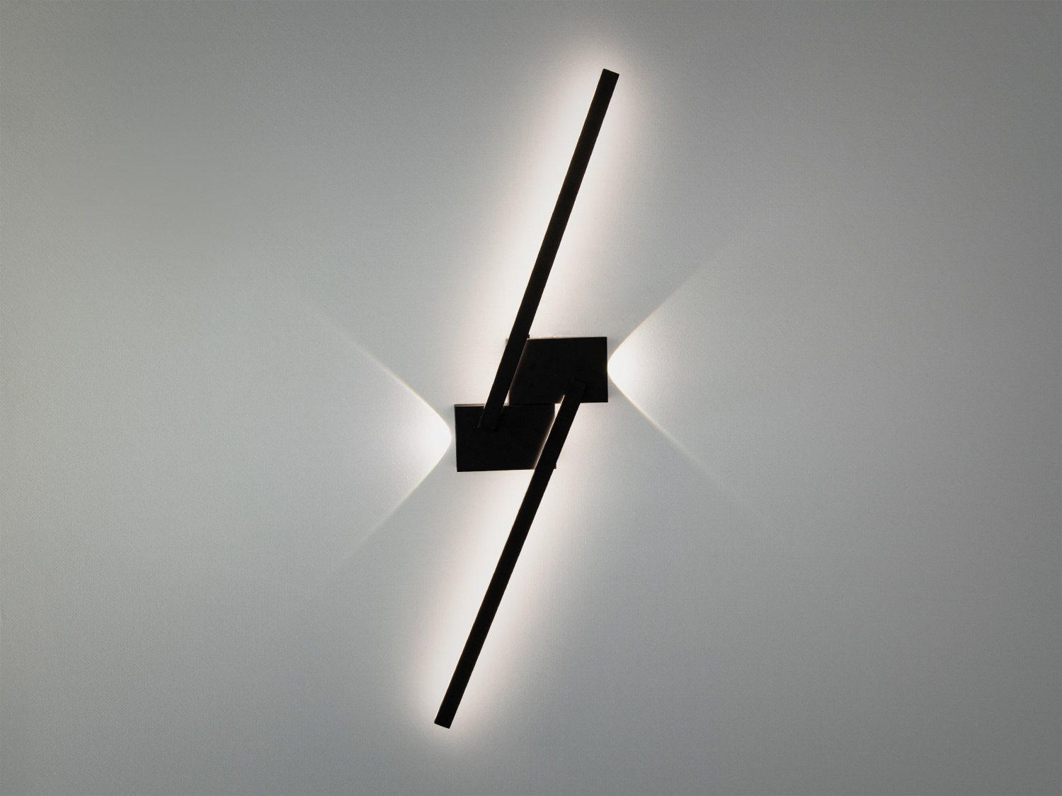Чорний настінний світильник з перехресними лініями, що випромінює тепле світло. Ідеальний для мінімалістичних просторів.