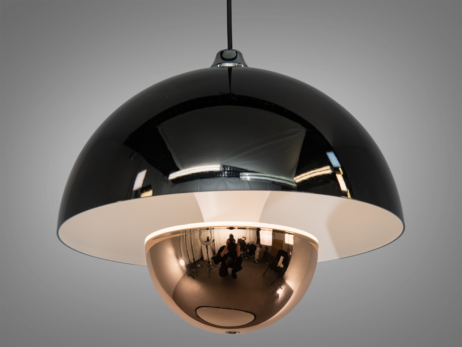 Підвісний світильник з гладким білим абажуром і дзеркальною сферою, що забезпечує м′яке розсіювання світла, підходить для вітальні.