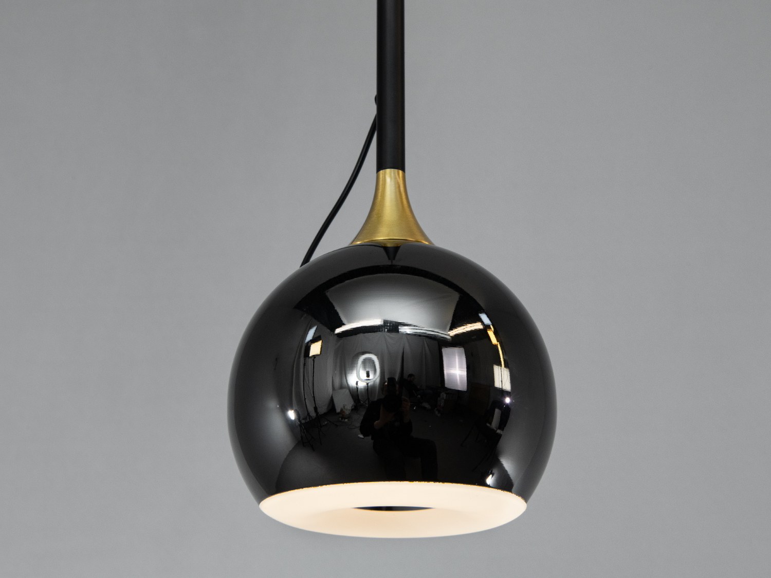 Крупний план чорного глянцевого плафона підвісного світильника з металевими акцентами, що додають елегантності.