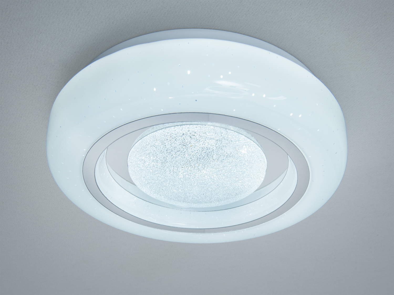 Стельова лампа з білим матовим корпусом та скляним центром, що створює м′яке розсіяне світло, ідеальна для спальні.