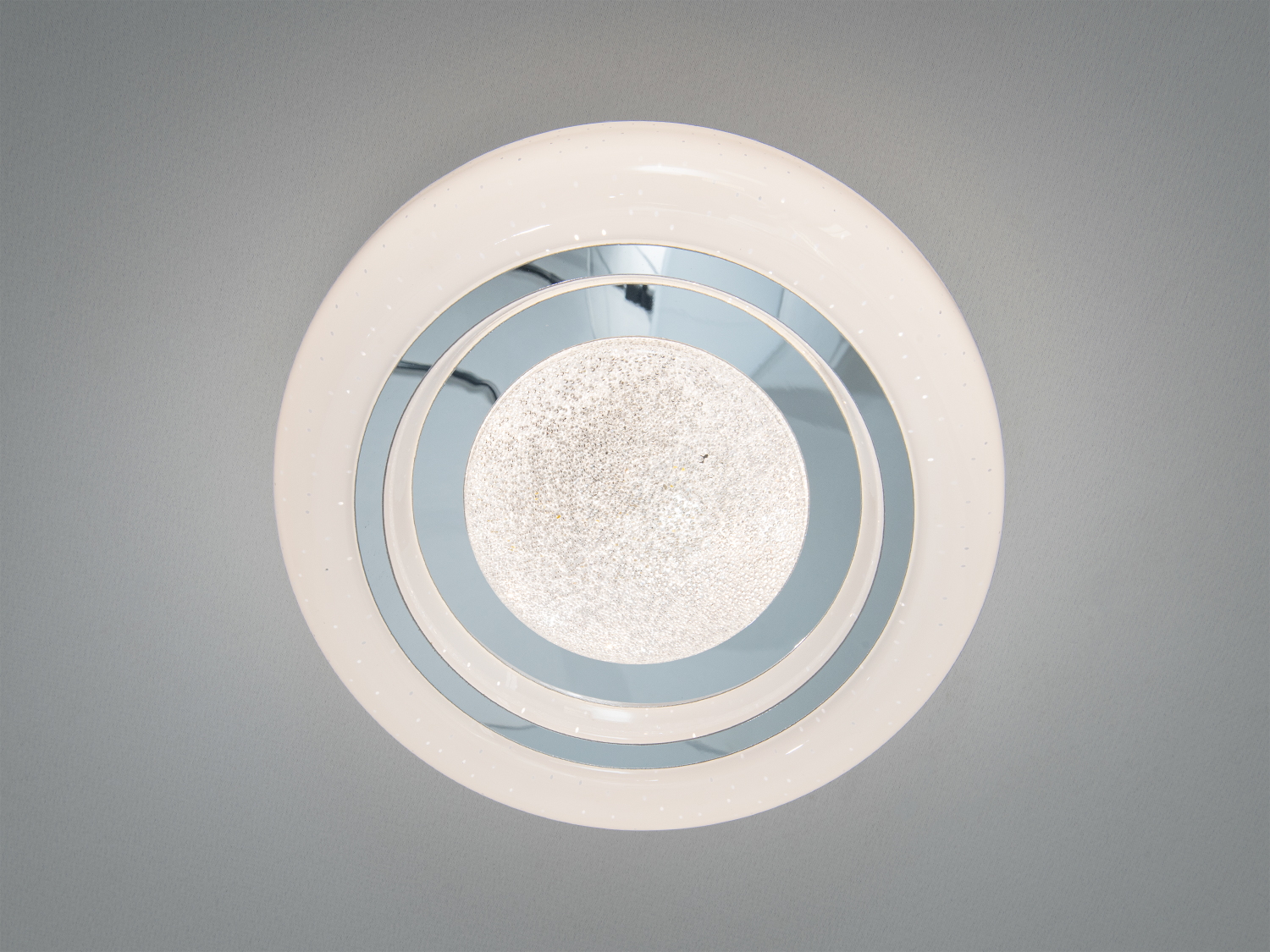 Стельова лампа з білим корпусом і дзеркальним скляним центром, що додає простору відчуття глибини.