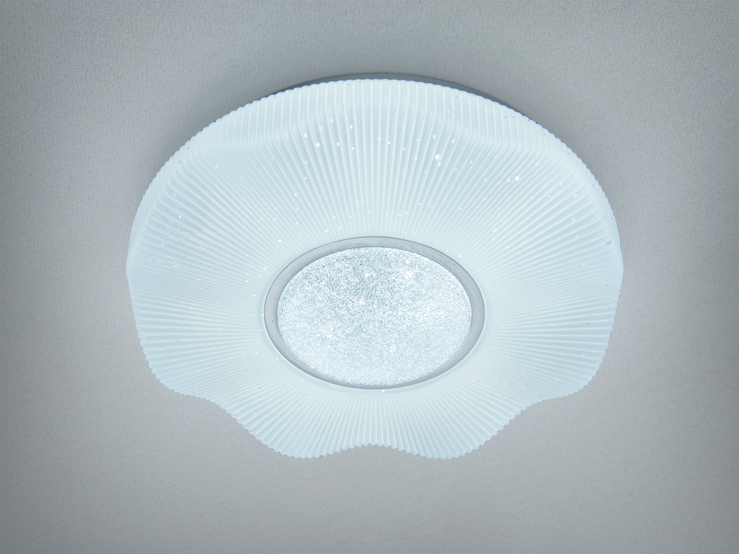 Плоский стельовий світильник з білим абажуром у вигляді хвиль. Вбудоване LED освітлення забезпечує м′яке розсіяне світло.